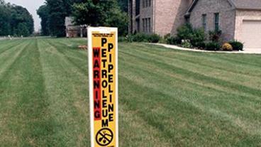 Pipepine warning post in a yard.