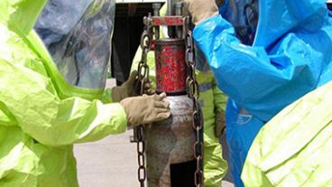 Two people in hazmat suits working with a chlorine device.