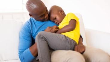 african american father comforting his ill son