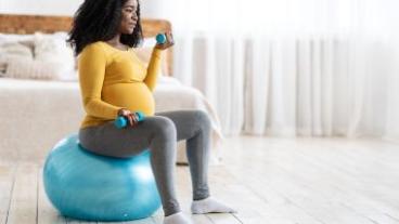Pregnant woman lifting weights on an exercise ball