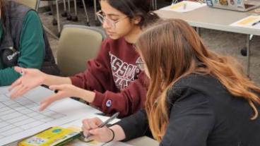 Two female students looking over work on a desk