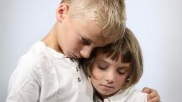 Two children hugging each other in grief
