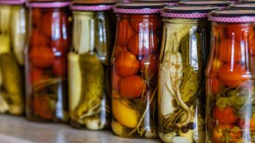 Jars of pickled vegetables lined up on a shelf