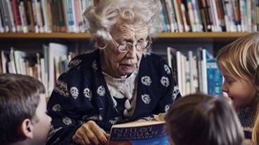 Older woman reading to young children
