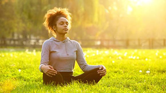 Black woman meditating outside.