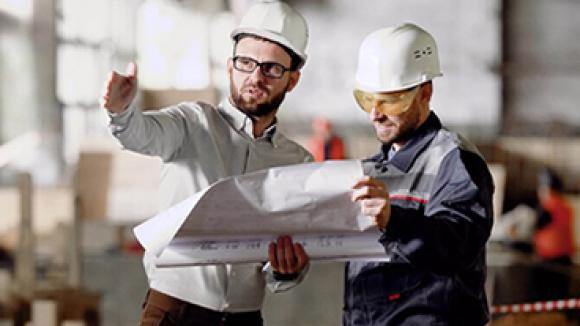 Two men in hard hats discussing building plans.