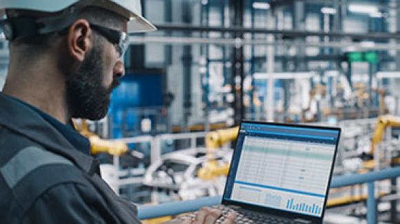 An engineer working on a laptop in a factory.