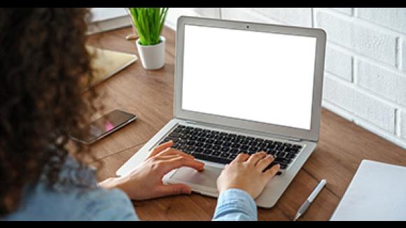 Woman sitting at a desk typing on a laptop