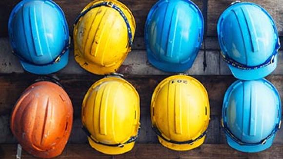 Different colored hard hats hanging on a wall.