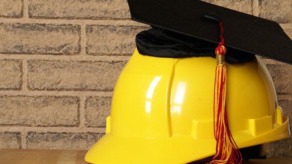 yellow hard hat with graduate mortar board on top