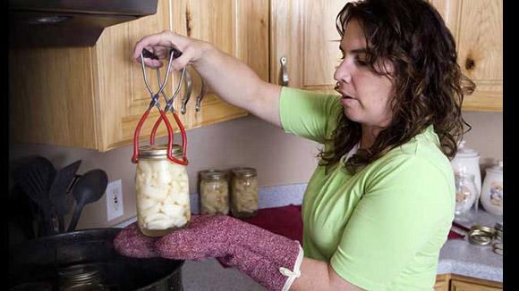 Woman lifting canning jar out of pot