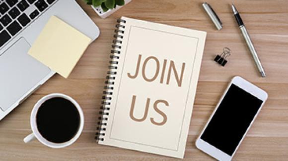 desk with a notebook that says join us