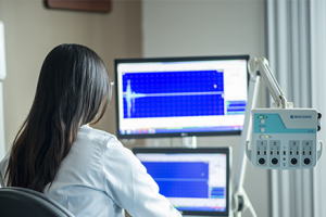 Indiividual with white lab coat viewwing computer monitor