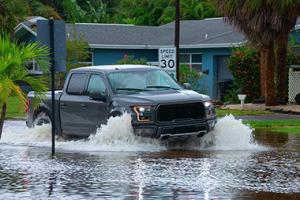 Truck driving on a flooded residential street.
