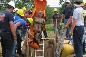 Fire fighters pulling a dummy out of a trench during training.