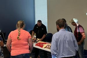 Class with an instructor teaching participants the difference cuts of meat on a cow