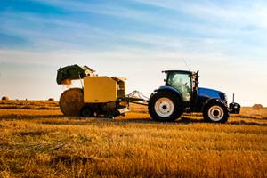 Farmer making hay bales with tractor and baler