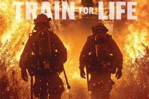 Two fire fighters walking into a fire.