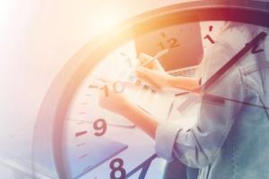 Person taking notes overshadowed by a clock