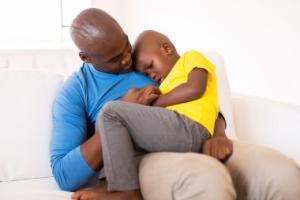 african american father comforting his ill son