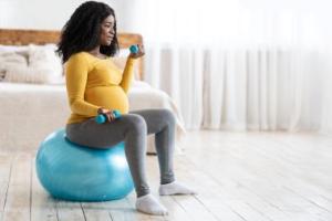 Pregnant woman lifting weights on an exercise ball