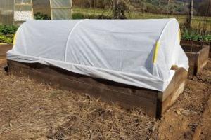 Cloth tunnel cover over a raised garden bed.