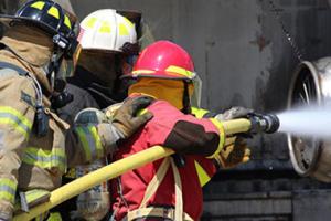 Firefighters pointing a water hose at an aircraft engine.