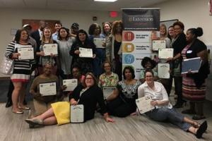 Graduates sitting and standing with their NLA certificates