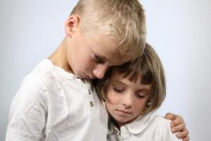 Two children hugging each other in grief