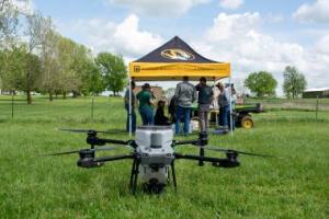 People Under an MU Extension Ten with a small drone on grass in the foreground