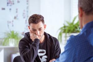 A man sitting with his chin on his hand.