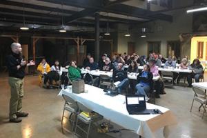 A man speaking to a group of people in a room.