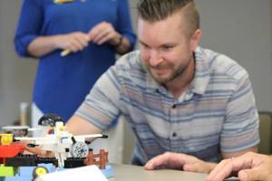 Man in conference room assisting with a Lego build.