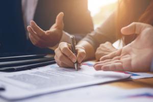 Two hands signing loan documents