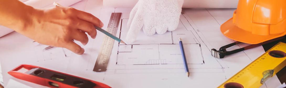 Building plans on a table with a hard hat and levels.