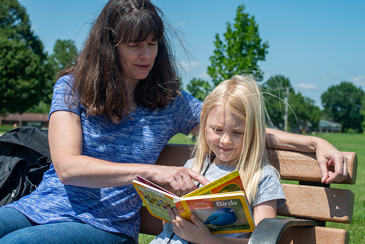 Grace Harris, right, and her mother, Kelly Harris, explore the contents of an Adventure Backpack, which includes such items as binoculars and fiction and nonfiction books.